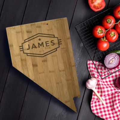 nevada state shaped bamboo cutting board with personalized engraving on wood table besides red tomatoes