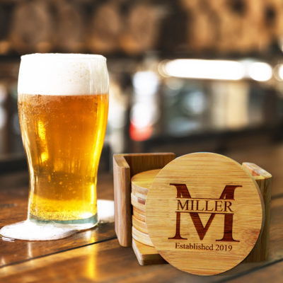 round bamboo coaster set on top o bar next to cold glass of beer