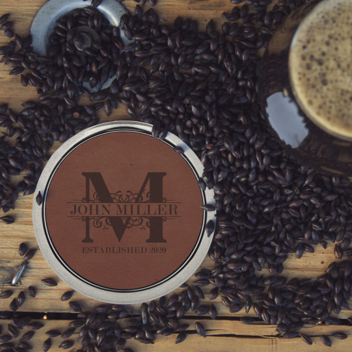 dark brown leatherette coaster with silver edges on top of table with coffee beans scatttered