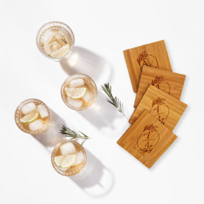 bamboo coaster set on white surface next to cold mixed drinks