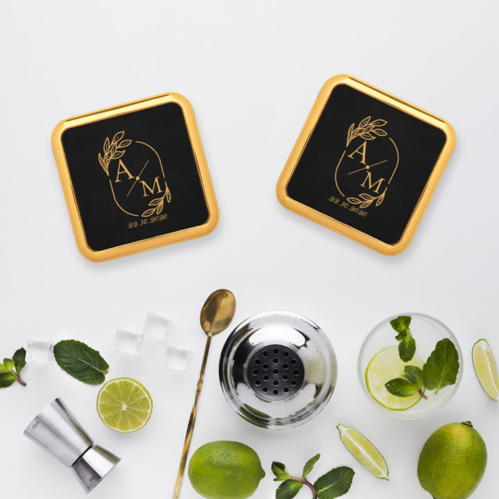 Square leatherette coaster with gold edge on top of marble table next to cold mojito drinks and mixer